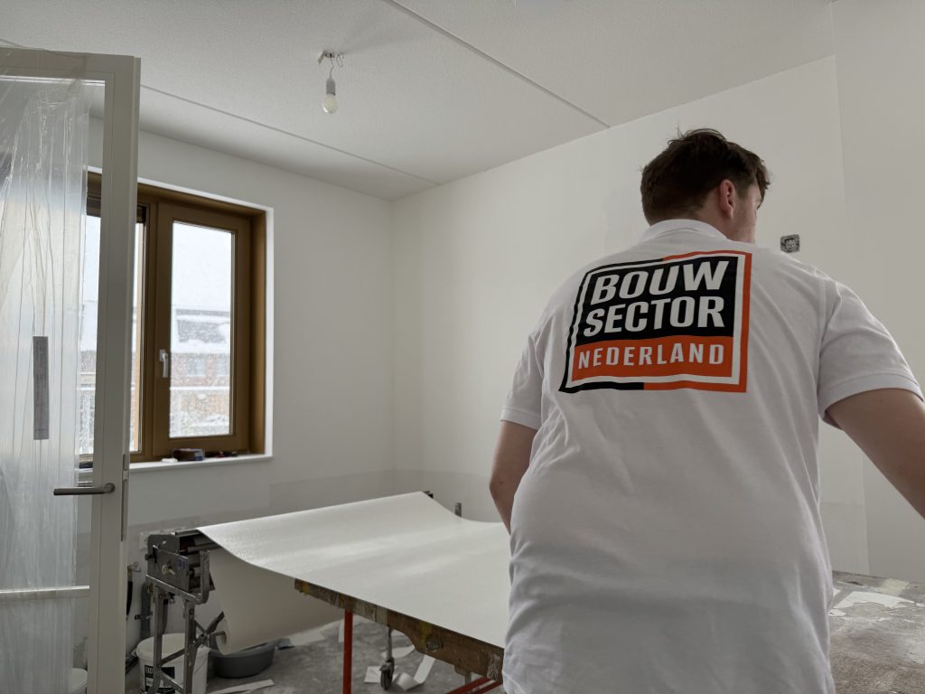 Behanger van Bouwsector Nederland rolt een baan renovlies uit over de plaktafel