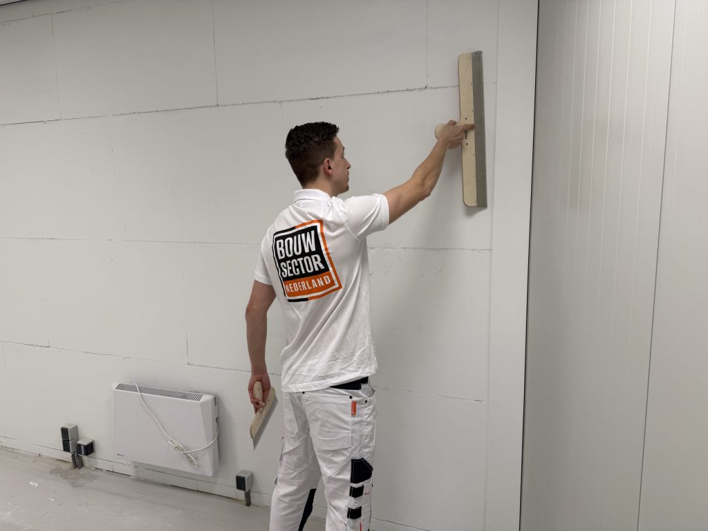 Stukadoor van Bouwsector Nederland trekt een wand vlak met een lange spaan