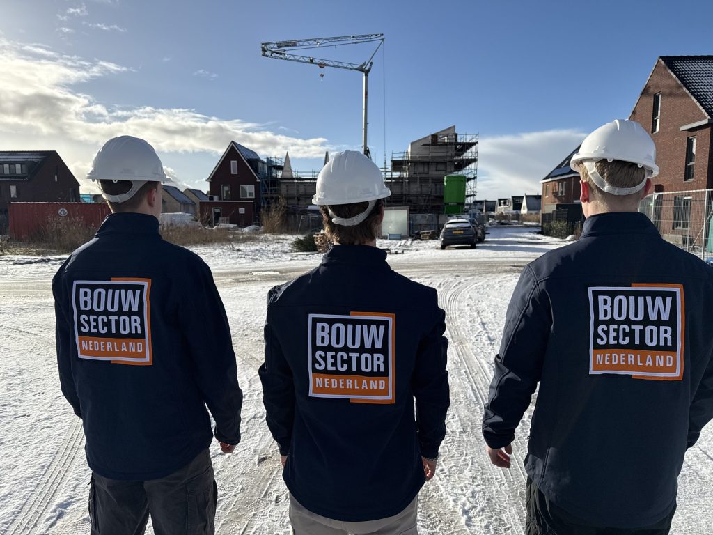 Drie collega's in werkjas van Bouwsector Nederland met bouwhelm bij nieuwbouwwoningen in aanbouw